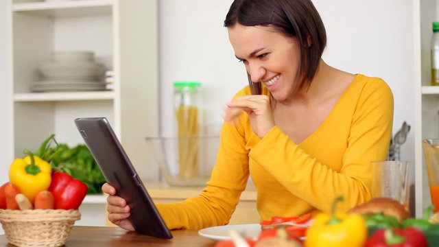 Woman having breakfast and chatting on tablet computer