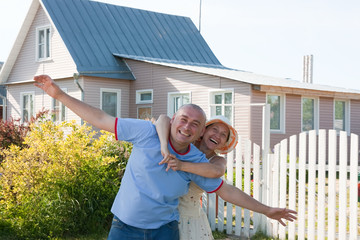 Happy man and woman near gate of  home