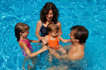 Happy family with kids in swimming pool. Summer vacation