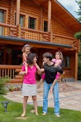 Happy smiling family near wooden house