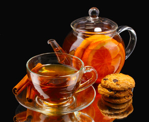 Glass teapot and cup with black fruit tea and cookies isolated
