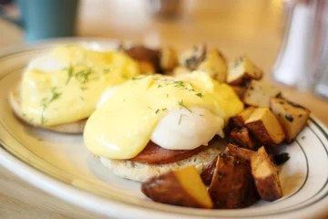 Foto op Canvas Delicious eggs benedict with seasoned potatoes for breakfast. © Peter Kim
