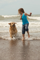 child playing with her dog by the ocean