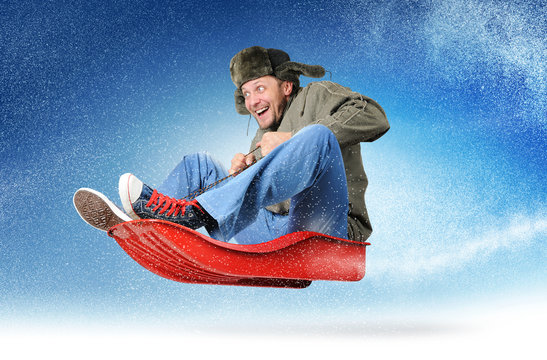 Cool young man fly on a sled in the snow