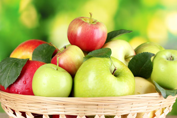 Fresh organic apples in basket on wooden table outside