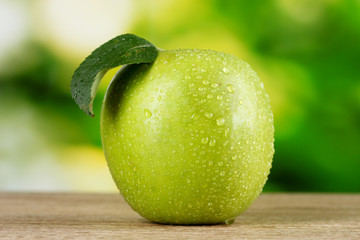 Healthy ripe dropped apple on wooden table outside