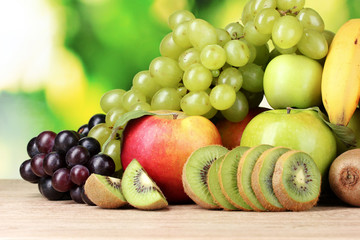 Ripe juicy fruits on wooden table on green background