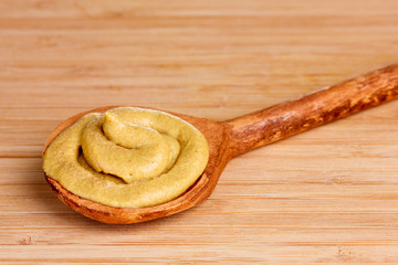 Mustard in wooden spoons on wooden background