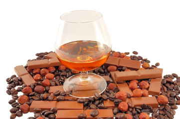 glass with cognac with chocolate, coffee and nuts