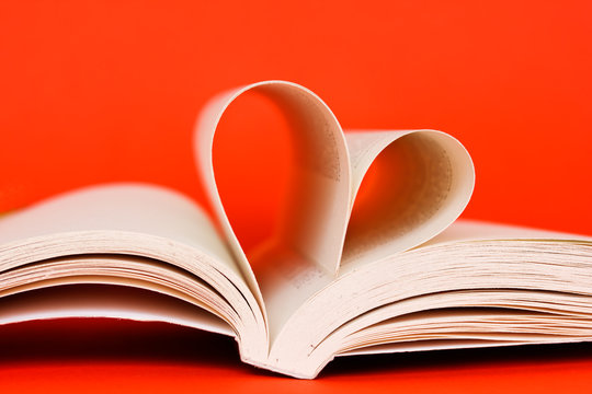 open book with heart of pages on orange background