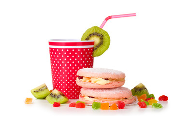 Red glass with a straw and two cakes isolated on white