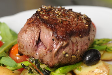 Steak mit Salat - auf grünem Spargel und Kartoffelscheiben