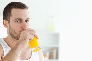 Fototapeta premium Portrait of a good looking man drinking orange juice