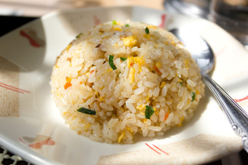 Round Chinese Fried Rice Served on a Dish with a Spoon Aside