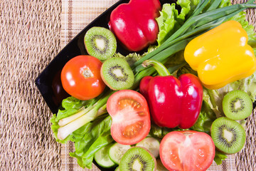 Varicoloured fruit and vegetables lie on a dish