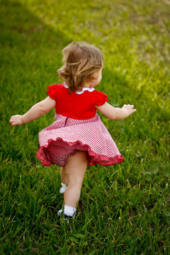 Girl Running Away in Red Dress in Grass