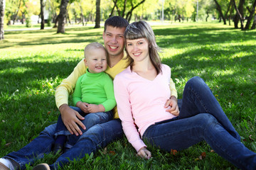 Fototapeta premium Young family with a child in summer park