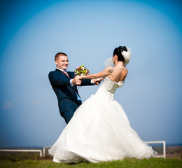 Newly married couple dancing in field