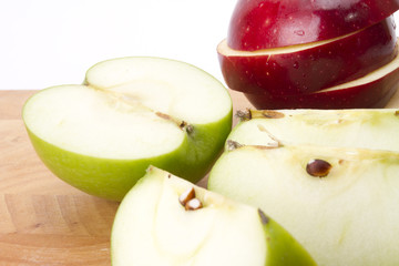 red and green apple cut and put on wood plate.