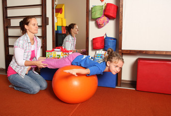 Kind bei der Physiotherapie mit Medizinball