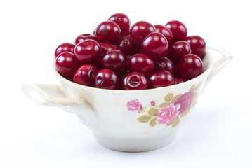 Bowl with ripe cherries. Isolated on a white background.