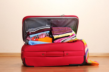 Open red suitcase with clothing in the room