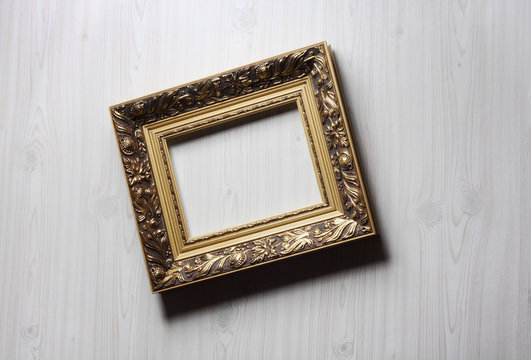 Image of lopsided golden art frame on the wall in dramatic light
