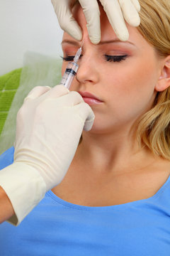 Young woman receiving cosmetic injection with syringe