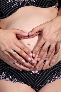 Babybauch mit Händen Herz Zeichen Nahaufnahme