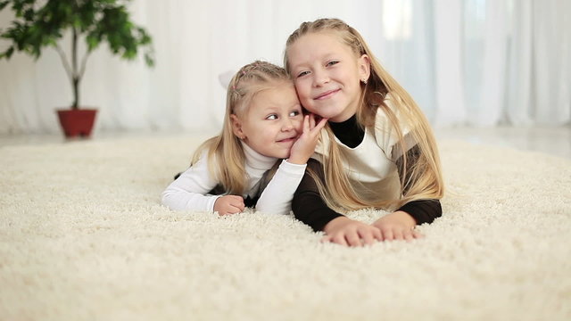 Two sisters lying on the floor and looking at camera