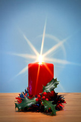 Christmas candle with starburst and holly.