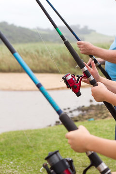closeup of three people holding fishing rods