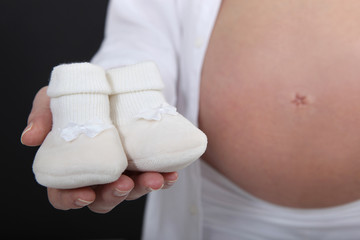 Pregnant woman holding her unborn baby's slippers