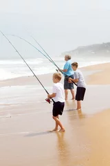 Foto op Canvas grandfather and two grandsons fishing on beach © michaeljung