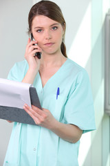 nurse holding chart and mobile telephone