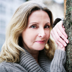 Frau an Baum gelehnt