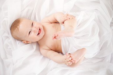 baby girl lying on white fabric and holding legs