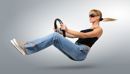 Young woman car driver in sunglasses with a wheel