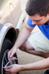 Young man checking tire pressure