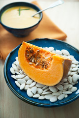 A piece of pumpkin on a plate with pumpkin seeds