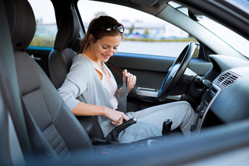 Pretty young woman driving her new car