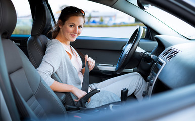 Pretty young woman driving her new car