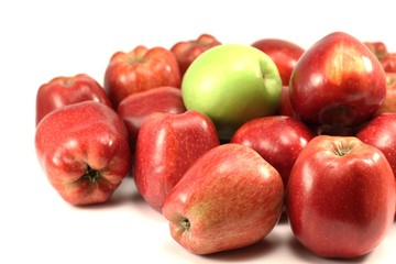 grüner Apfel zwischen roten Äpfeln