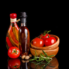 Tomatoes and garlic in wooden plate on black background.