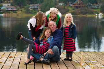 A happy gray haired Grandpa with 4 Grandchildren on a lake