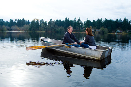 Happy couple in love rowing a small boat on a quiet lake