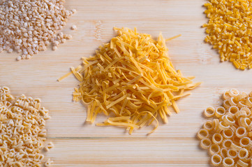 Different types of noodles arranged in piles on wooden table