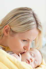 Affectionate mother kissing her sleeping baby's cheek