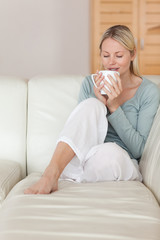 Woman on the sofa taking a sip of coffee