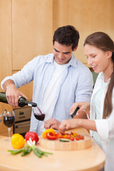 Portrait of a cute man pouring a glass of wine while his wife is